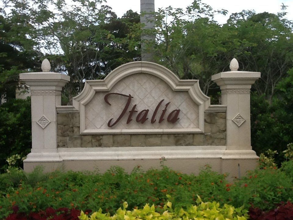 Decorative stone entrance sign reading “Italla” with greenery and trees behind it