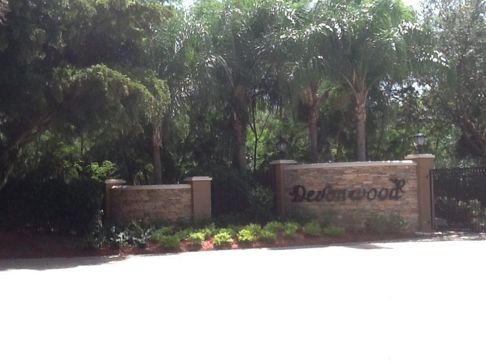 Stone entrance sign reading “Belemwood” surrounded by lush green trees and plants