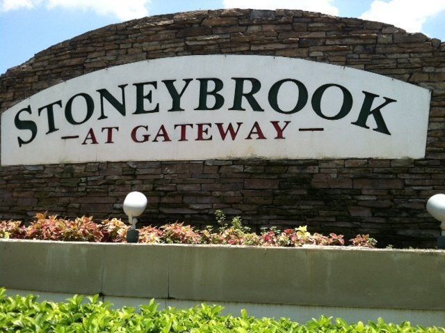 Stone sign reading “Stoneybrook at Gateway” with flowers and greenery in front