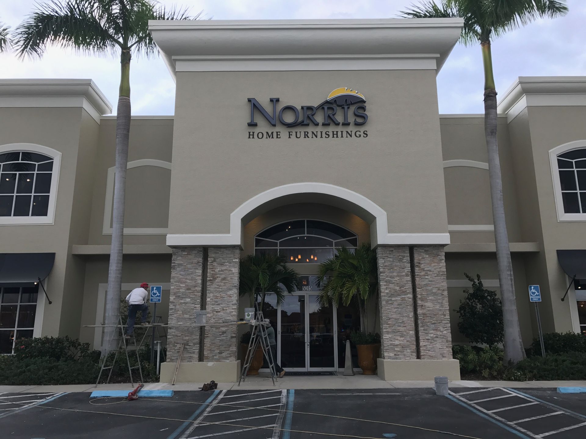 North entrance of Norris Town & Country, a beige stucco building with stone columns and palm trees.