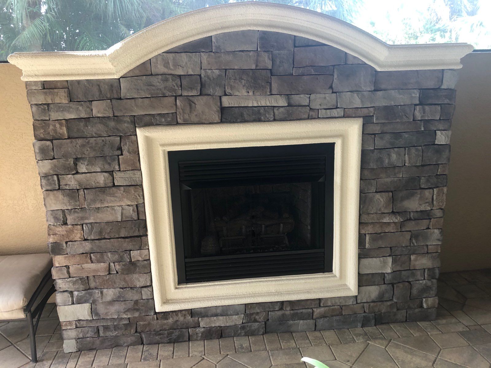 Stone fireplace with a white mantel and dark firebox, centered in a living room.