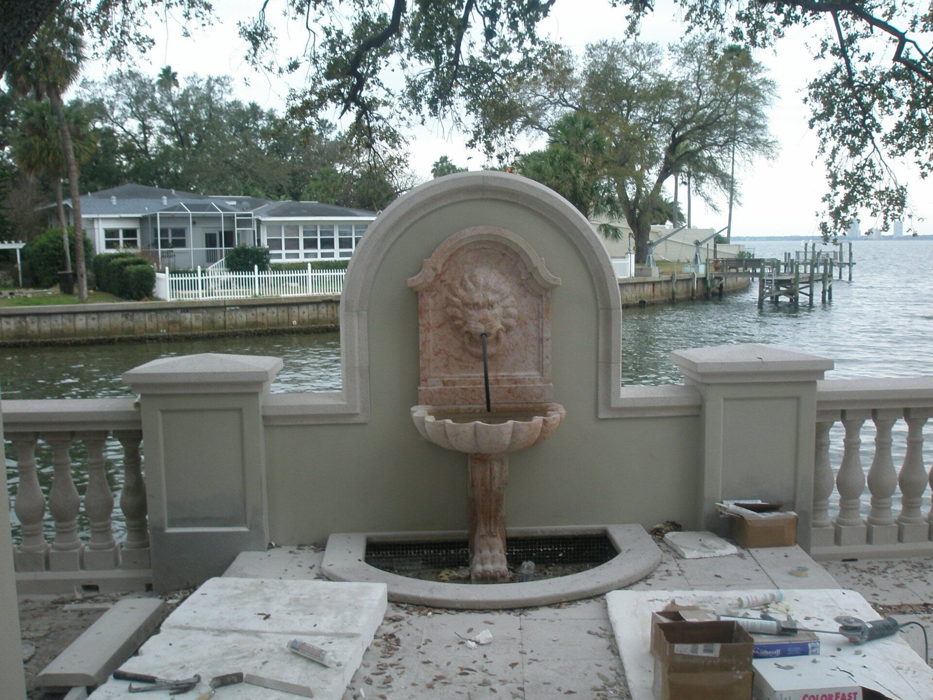 Decorative fountain on a waterfront terrace with stone balustrades and trees in the background