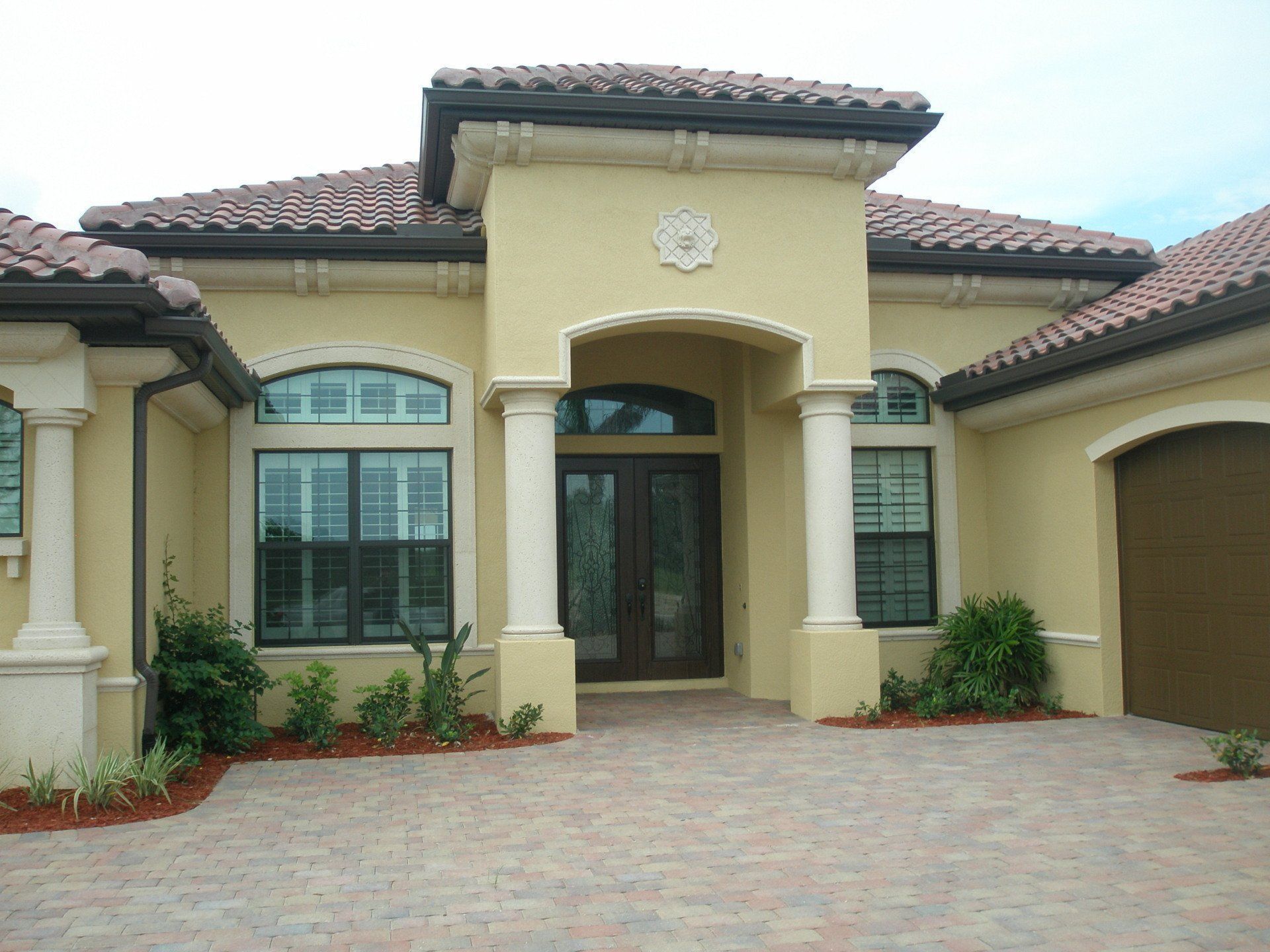 Stucco suburban house with arched entry, tiled roof, and a paved driveway