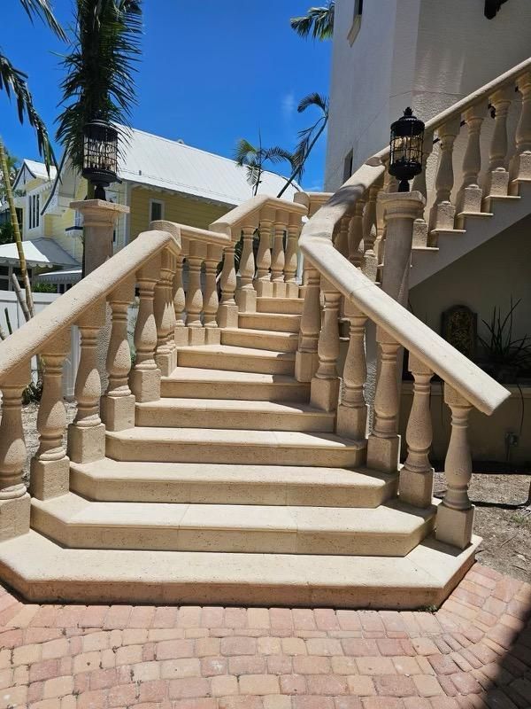 Beige outdoor staircase with balustrades leading to a sunlit building under a blue sky