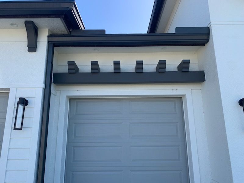 White garage door under a modern house overhang with dark beams and trim.