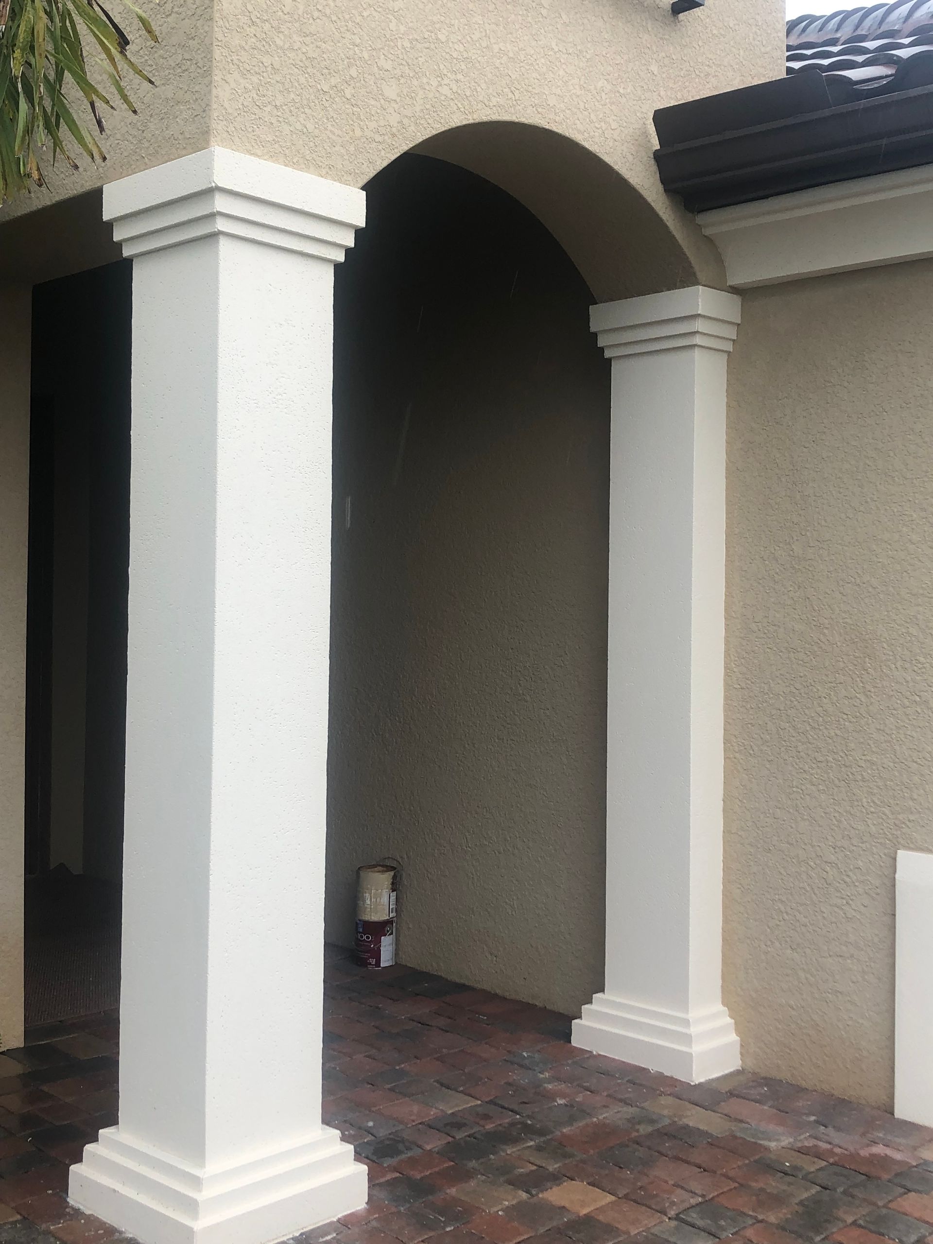 Covered entryway with white columns, arched ceiling, and dark tiled floor leading to a recessed alcove.