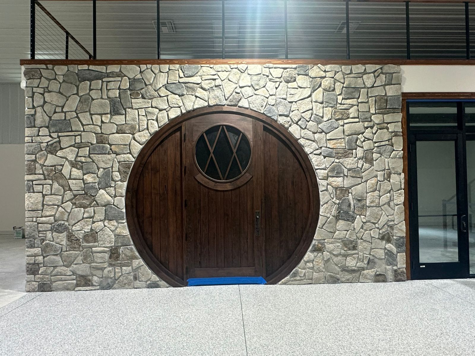 Stone wall with a large round wooden door and small circular window above it