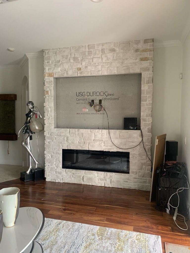 Modern living room with a stone fireplace, hardwood floors, and a white vase on a table.