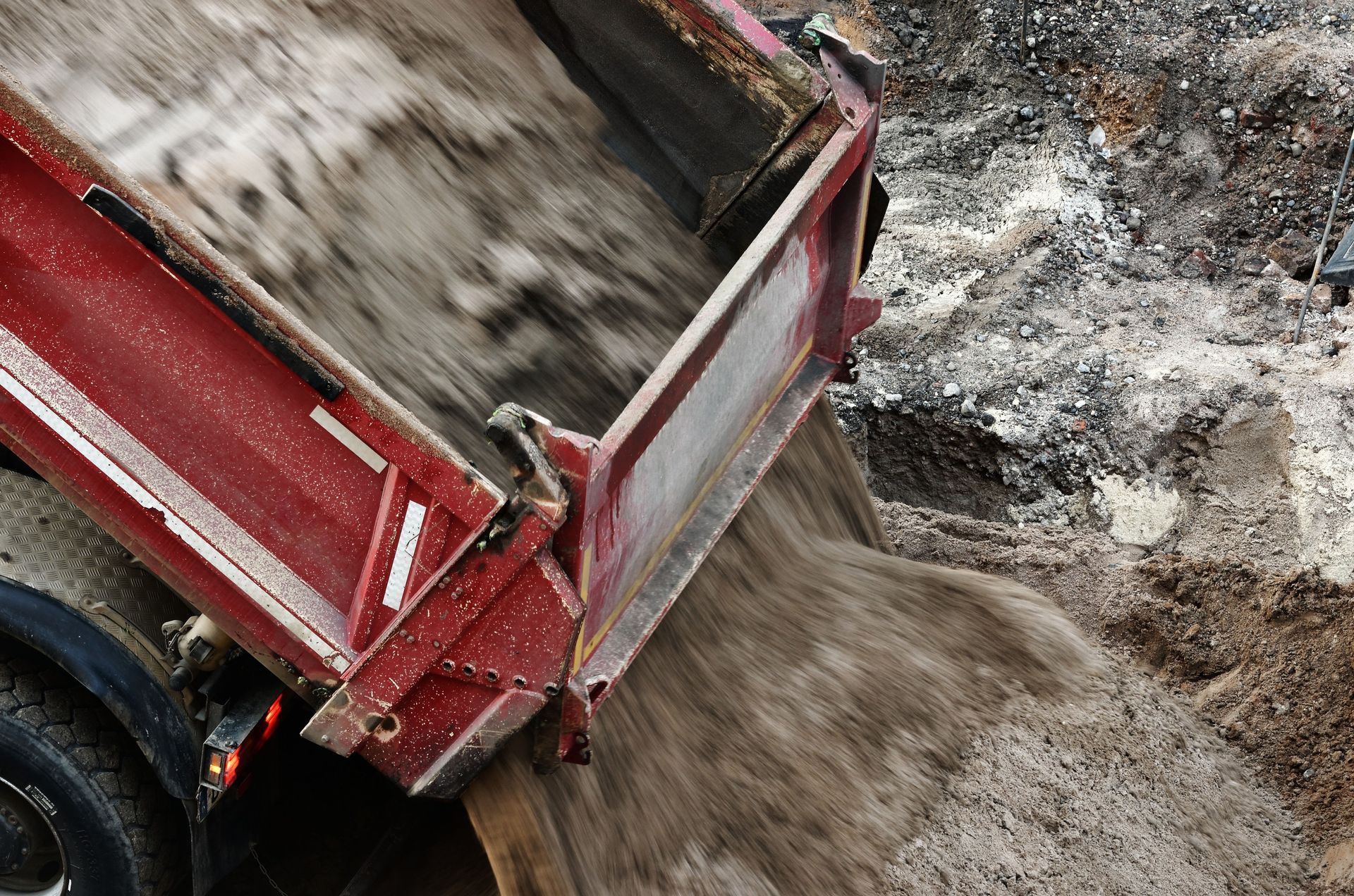 Red dump truck unloading gravel.