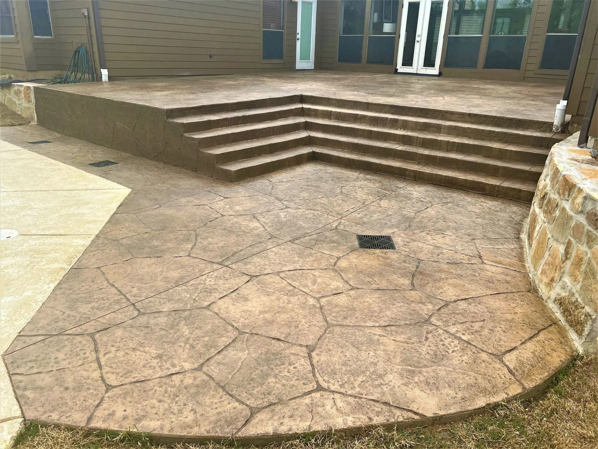 Concrete courtyard with cracked stamped paving and steps leading to a building entrance.