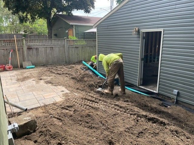 A man is digging in the dirt in front of a house.
