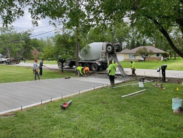 A concrete mixer truck is pouring concrete into a driveway.