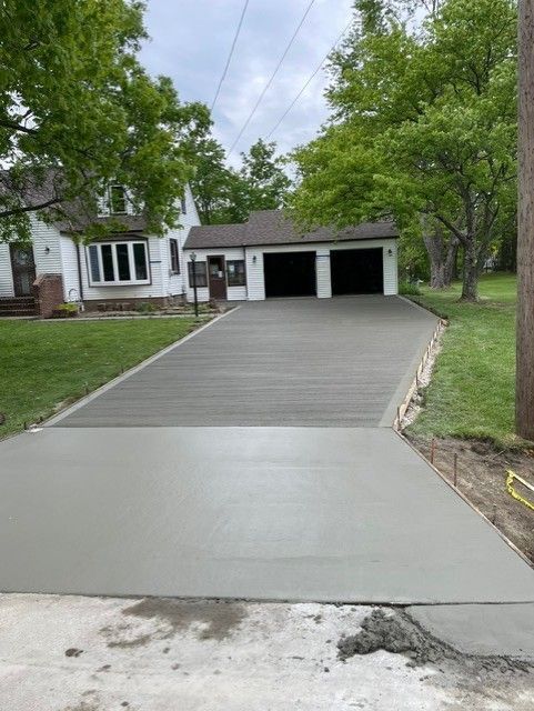 A concrete driveway is being built in front of a house.