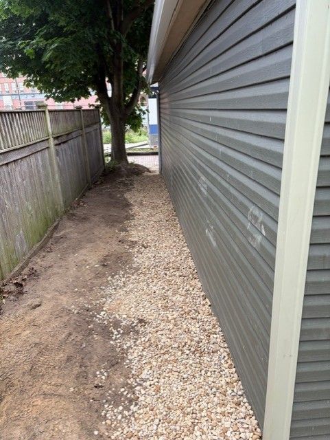 A gravel path leading to a garage with a tree in the background