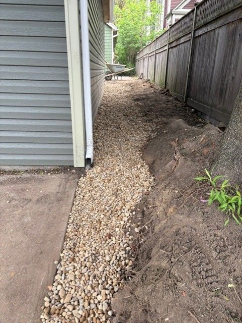 A gravel path leading to a house next to a wooden fence.