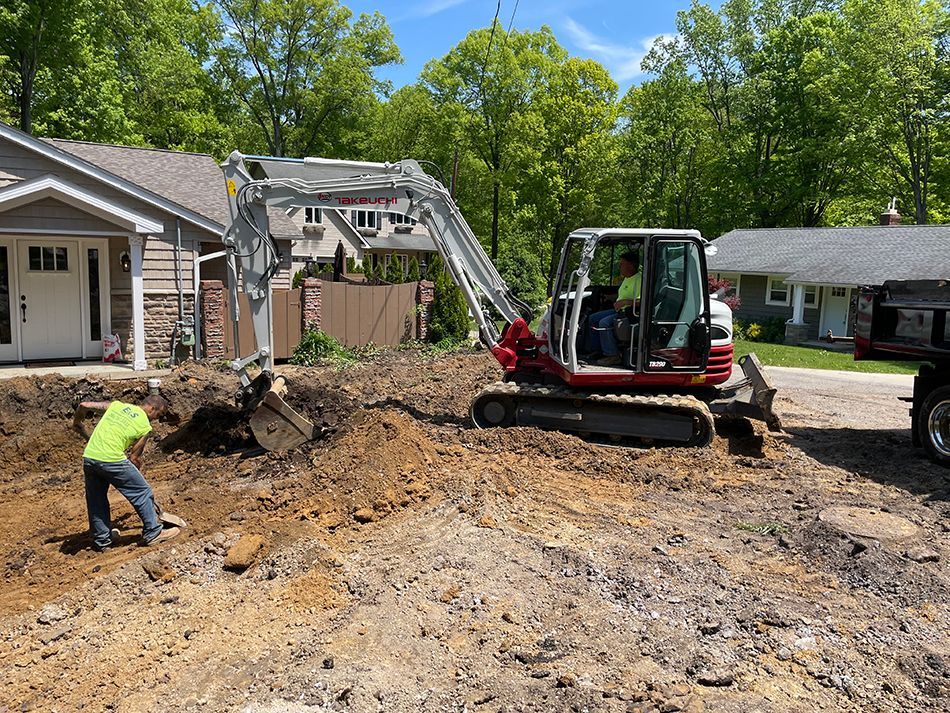A man is digging a hole in the dirt in front of a house.