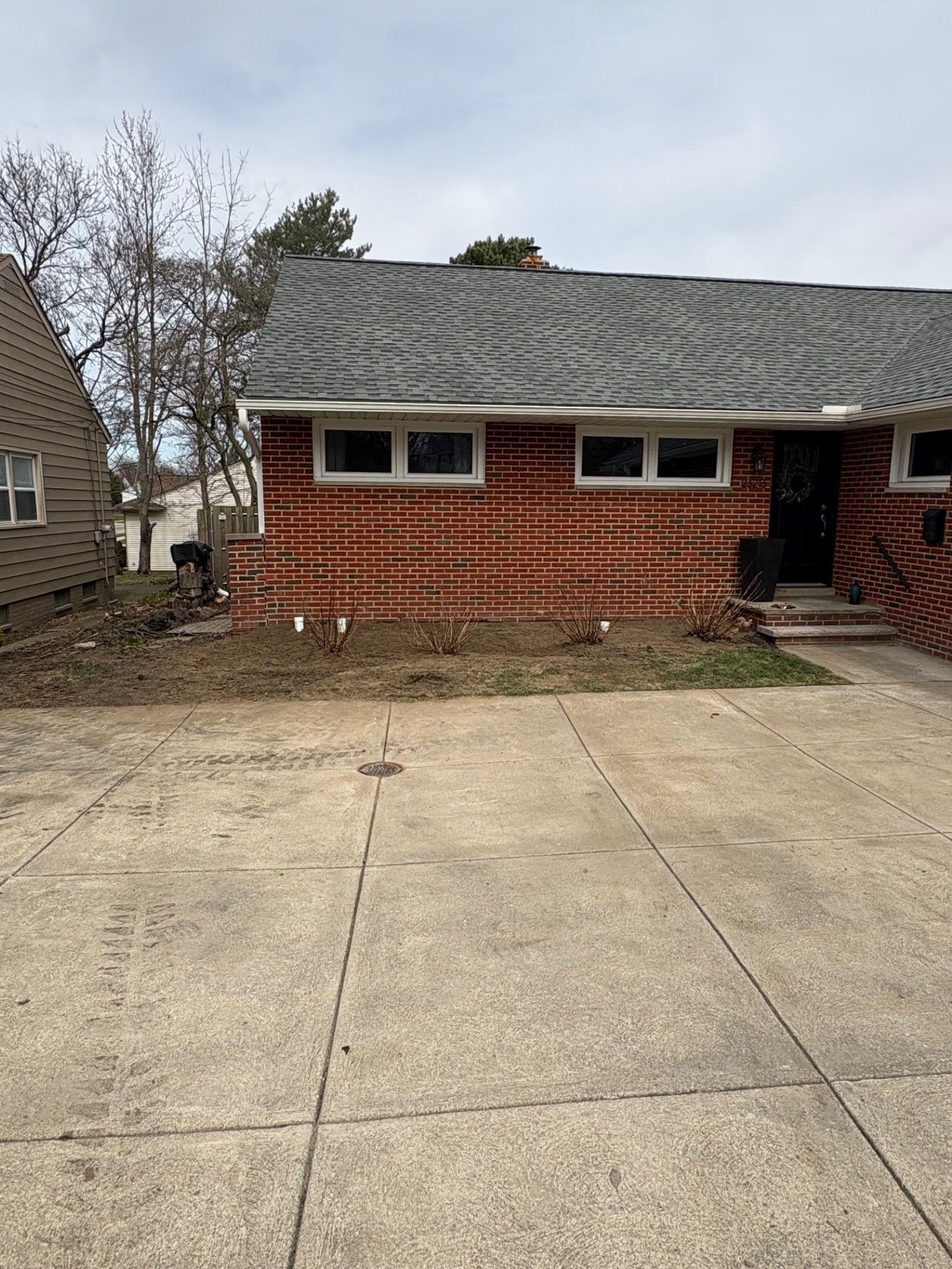 A brick house with a gray roof and a driveway in front of it.
