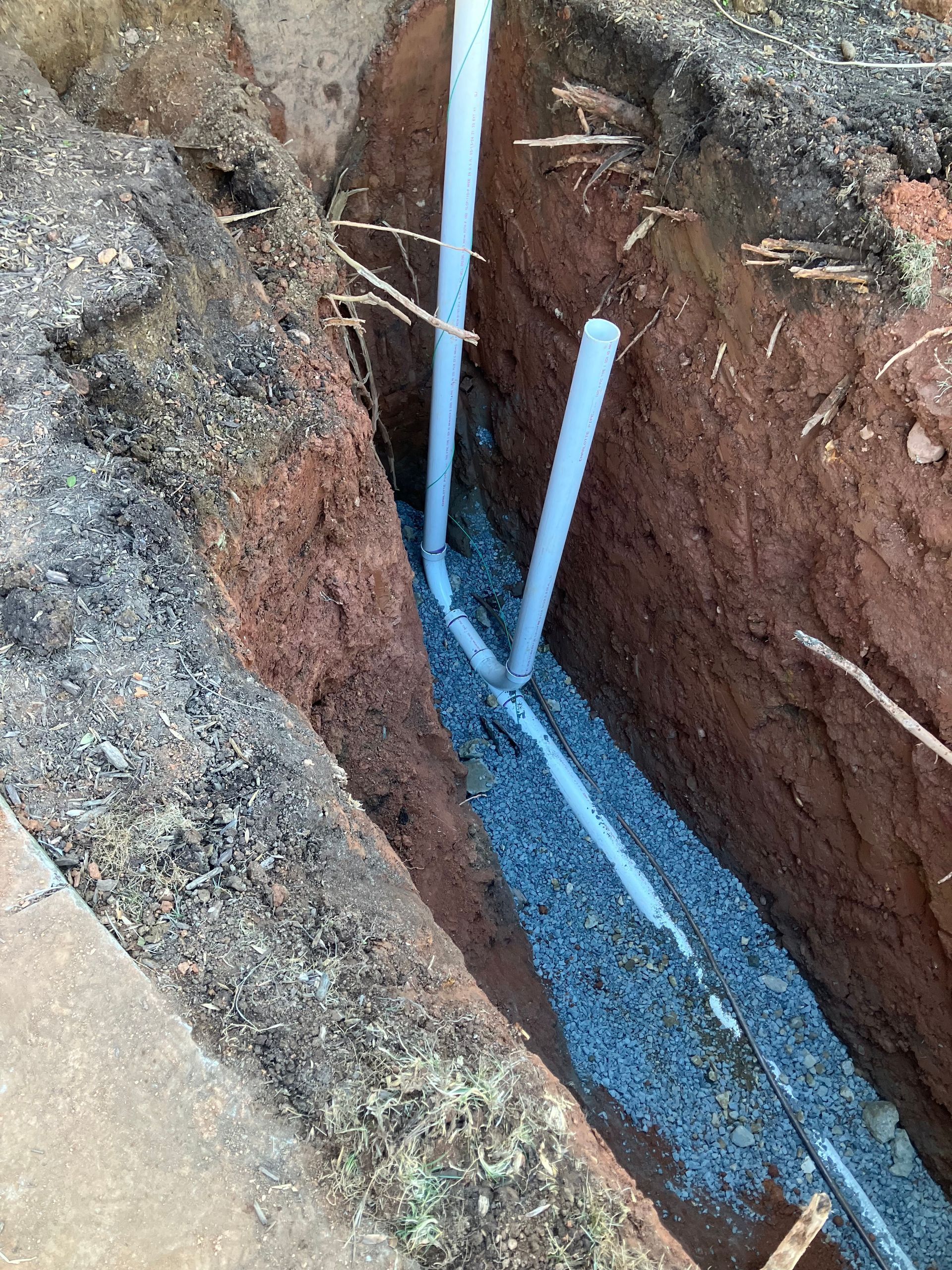 A white pipe is being installed in a hole in the ground.