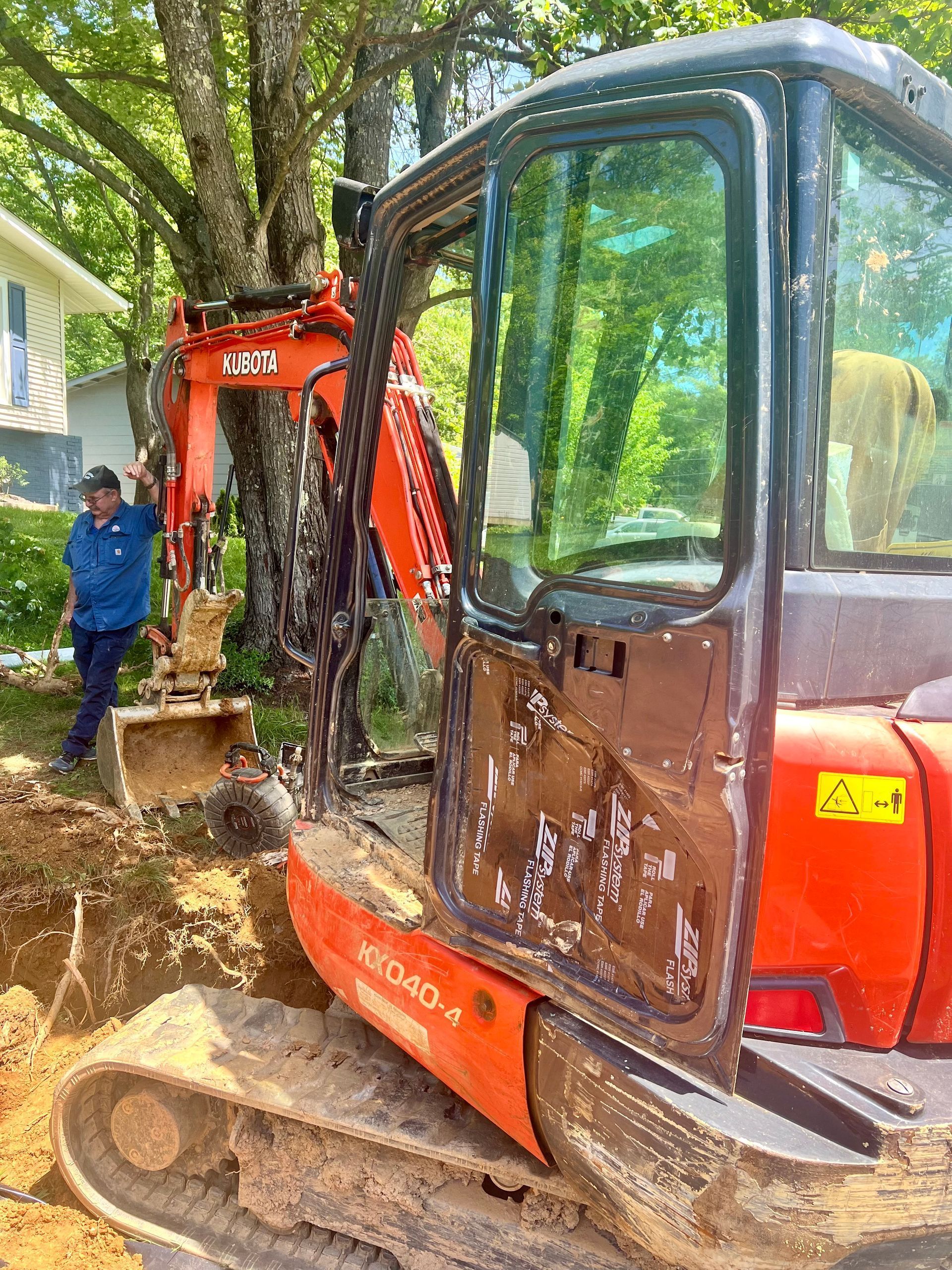 A man is standing next to a muddy excavator.