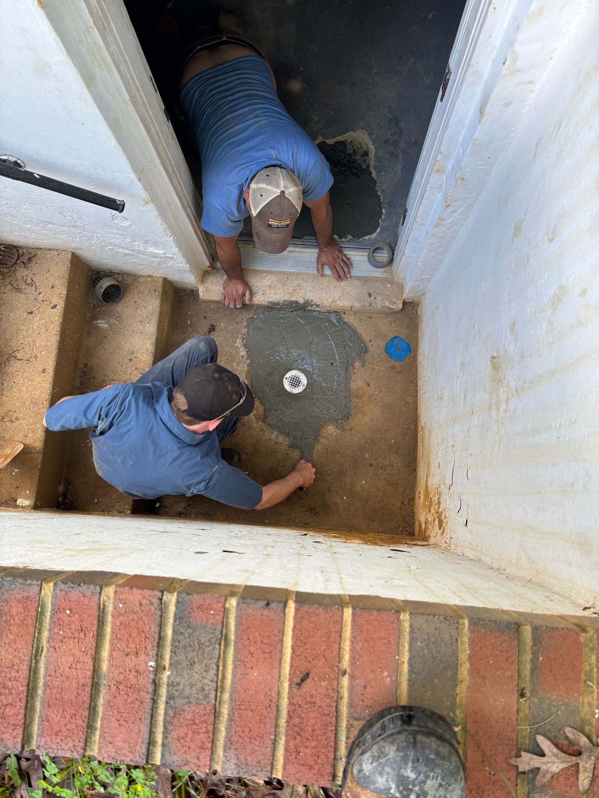 Two men are working on the floor of a basement.
