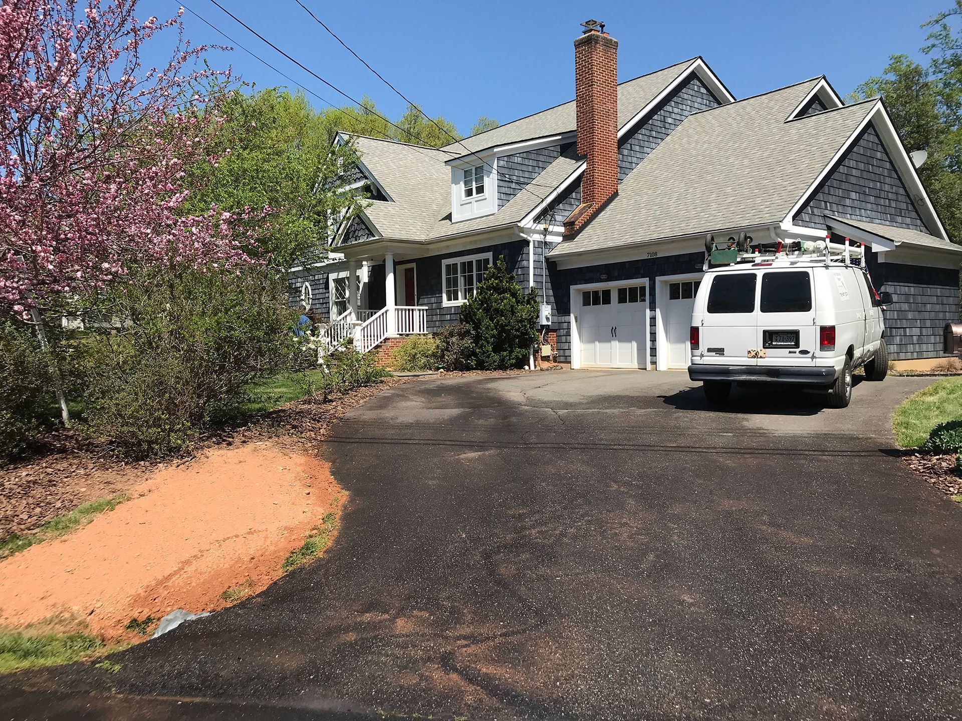 A white van is parked in front of a large house.