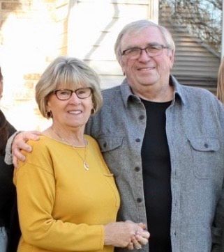 A man and a woman wearing glasses are smiling for the camera.