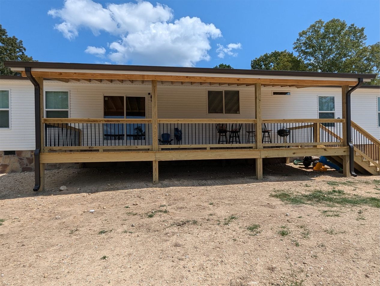 A mobile home with a large wooden deck and stairs.
