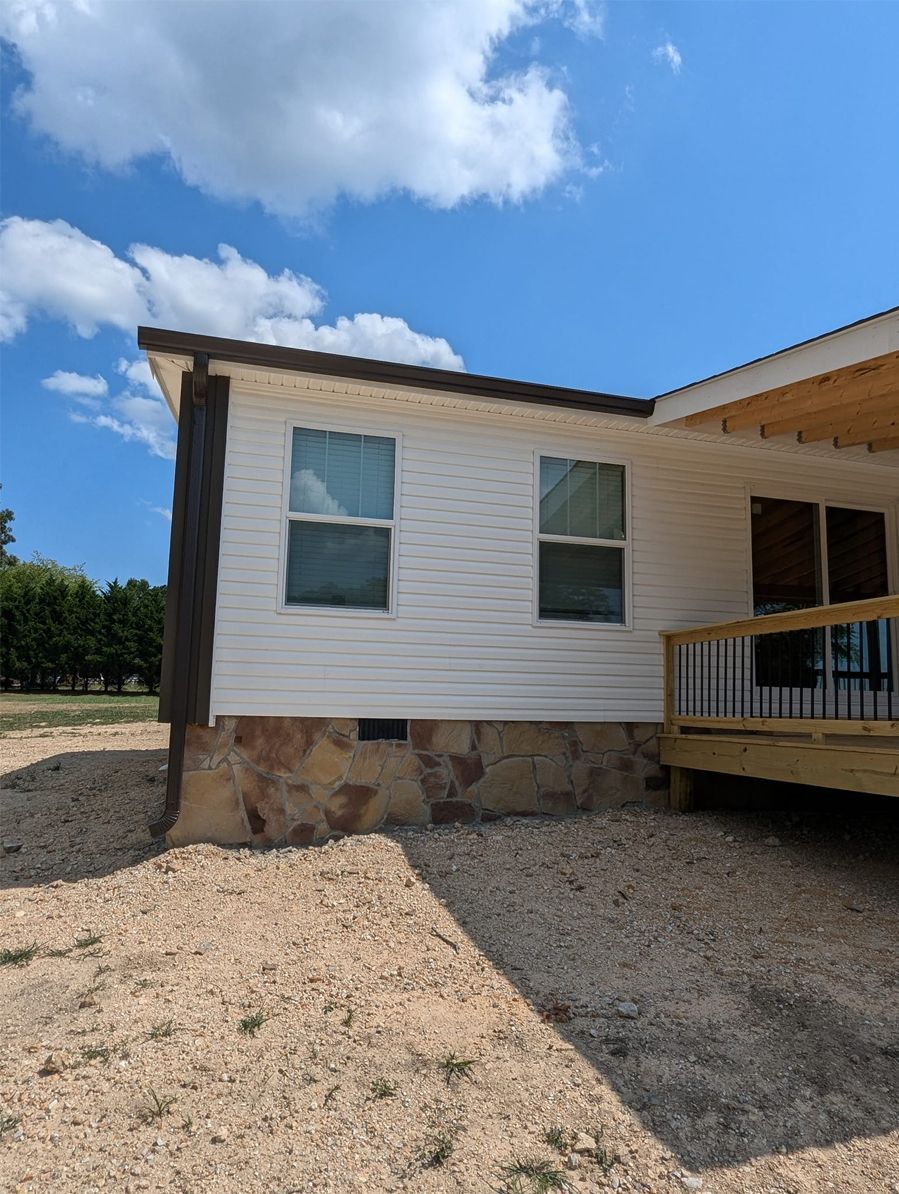 A white house with a wooden deck and a blue sky in the background.