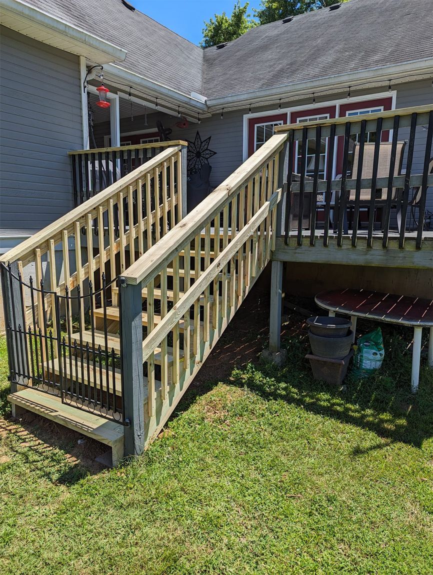 A wooden deck with stairs leading up to it in front of a house.