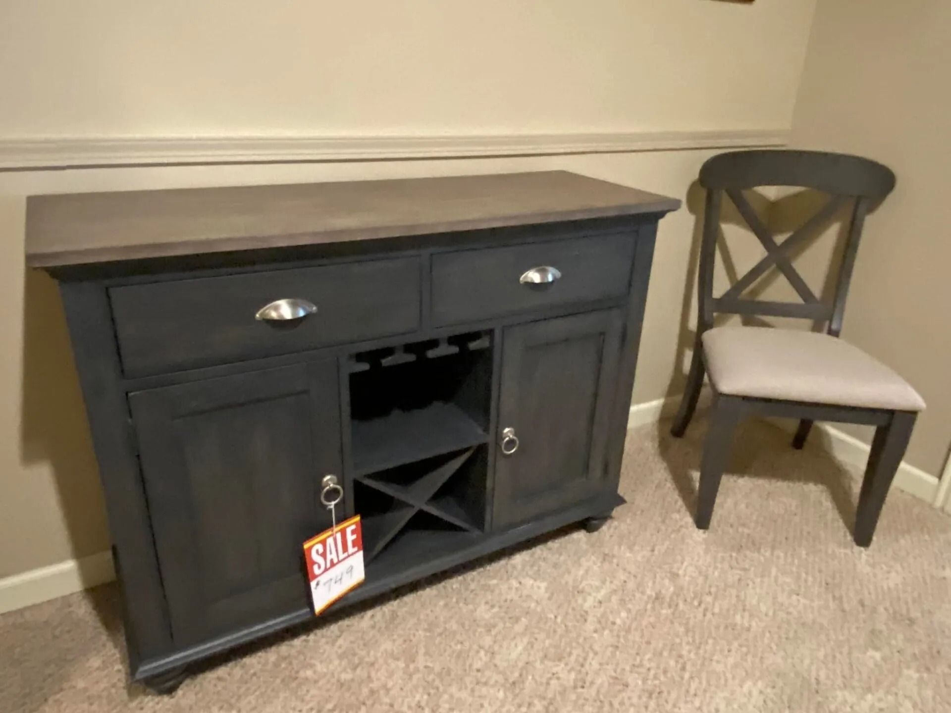Dark gray buffet cabinet with wine rack, two drawers, and a wooden chair on a carpet.
