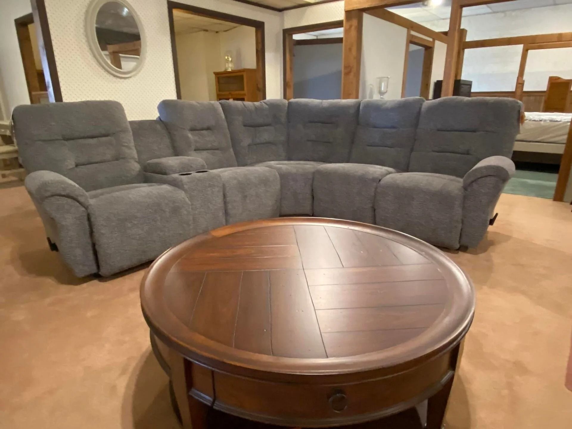 Gray sectional sofa with cup holders, brown coffee table in showroom.