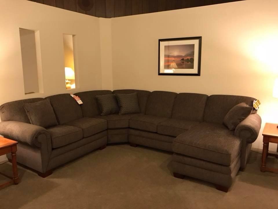 Brown sectional sofa in a room with neutral walls, rug, and wooden accents.