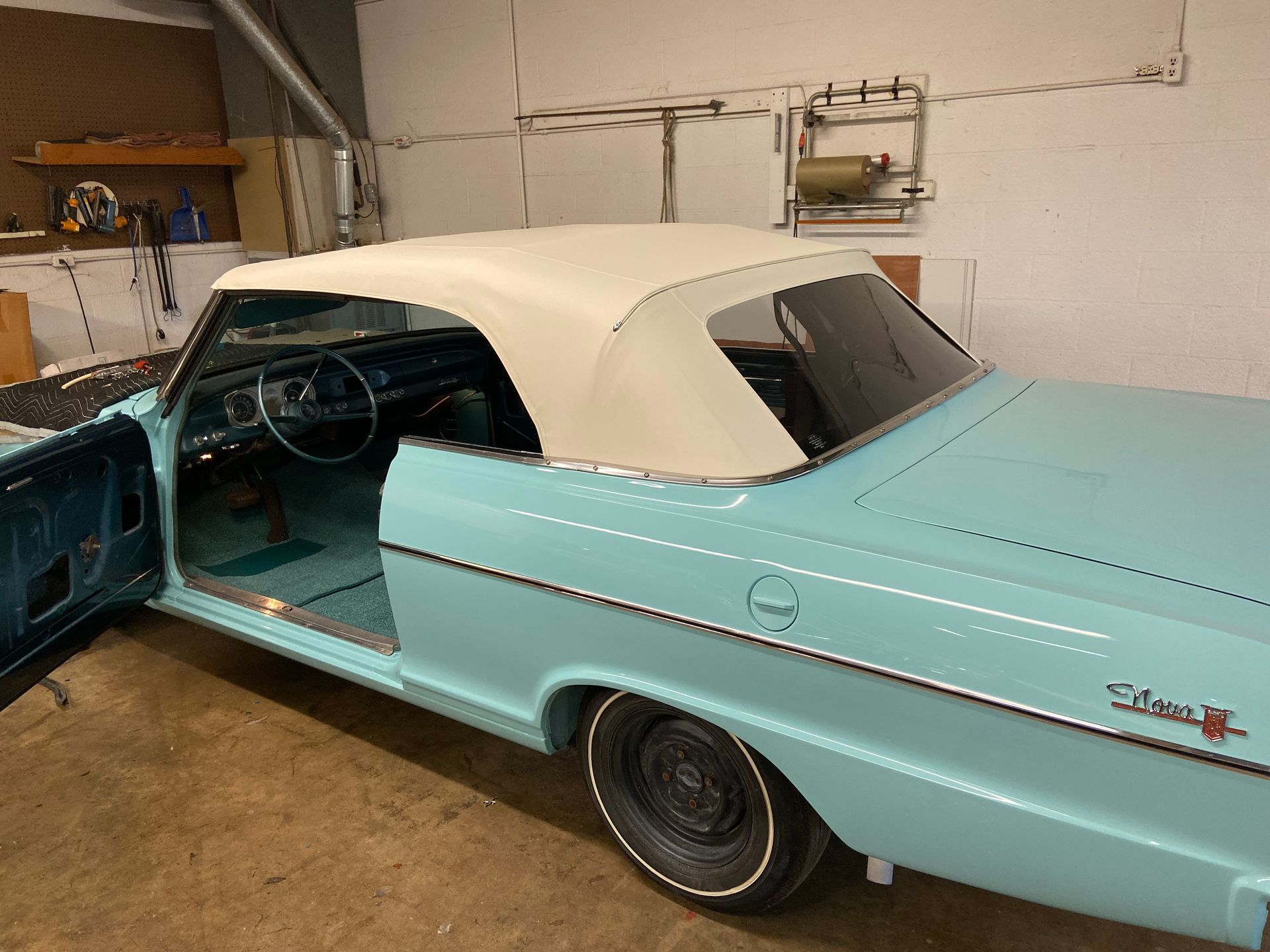 Light blue convertible car with a white top, inside a garage.