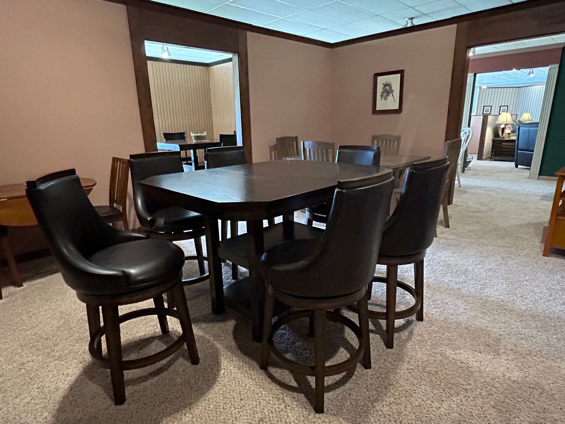 Dining room set: dark wood table and chairs with leather upholstery, in a room with beige carpet.