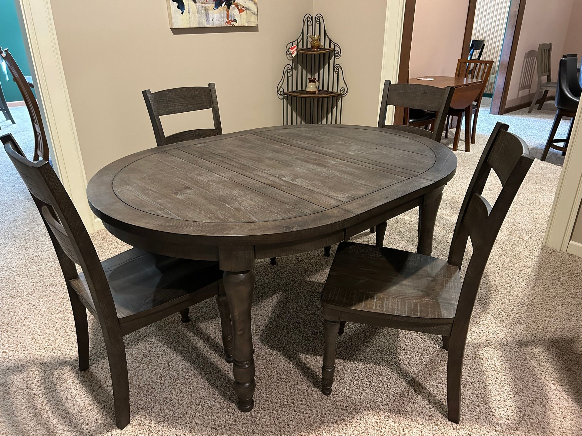 Wooden dining table with four matching chairs in a room with beige carpet.