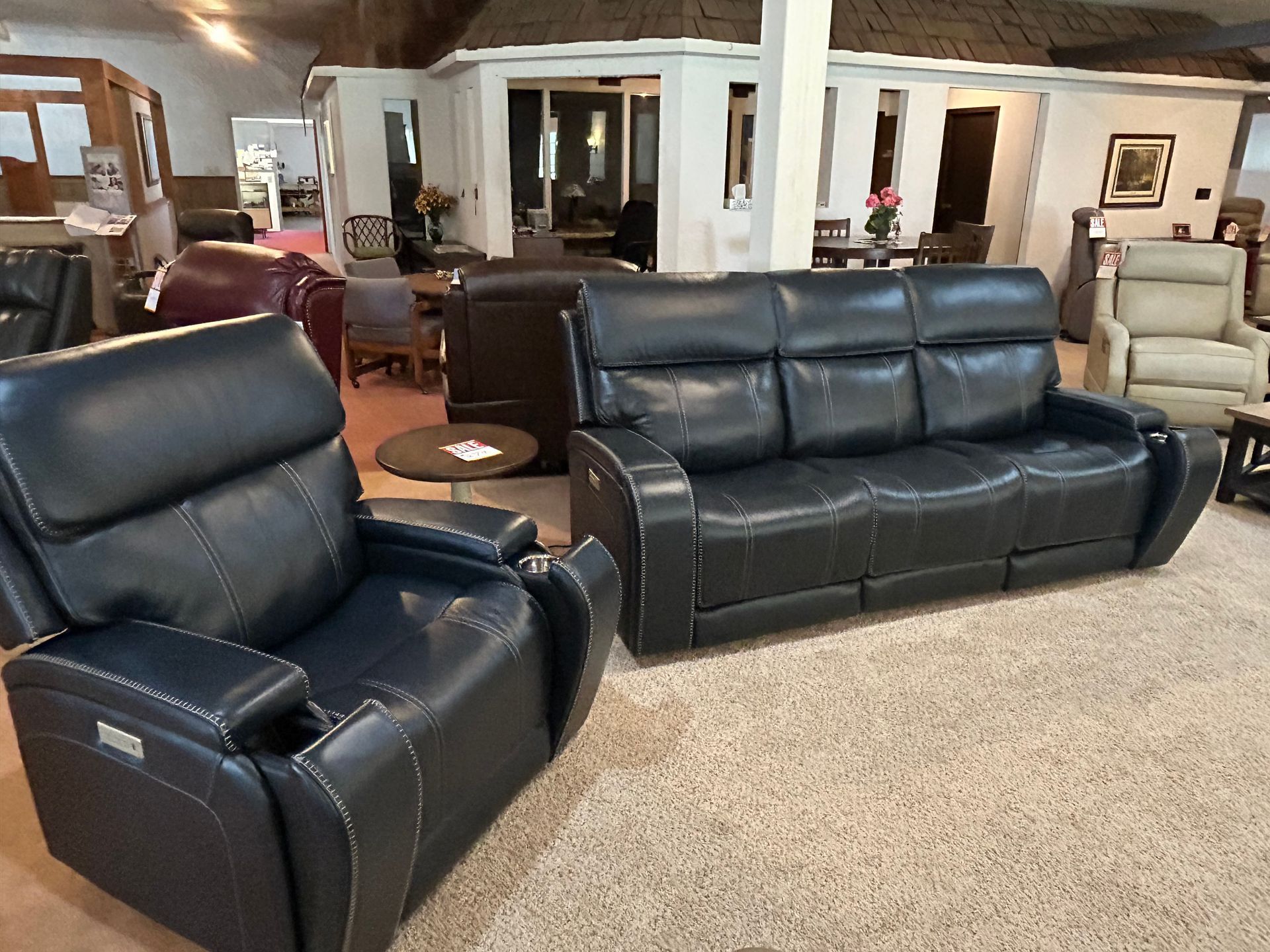 Blue leather reclining sofa and chair displayed in a furniture store setting.