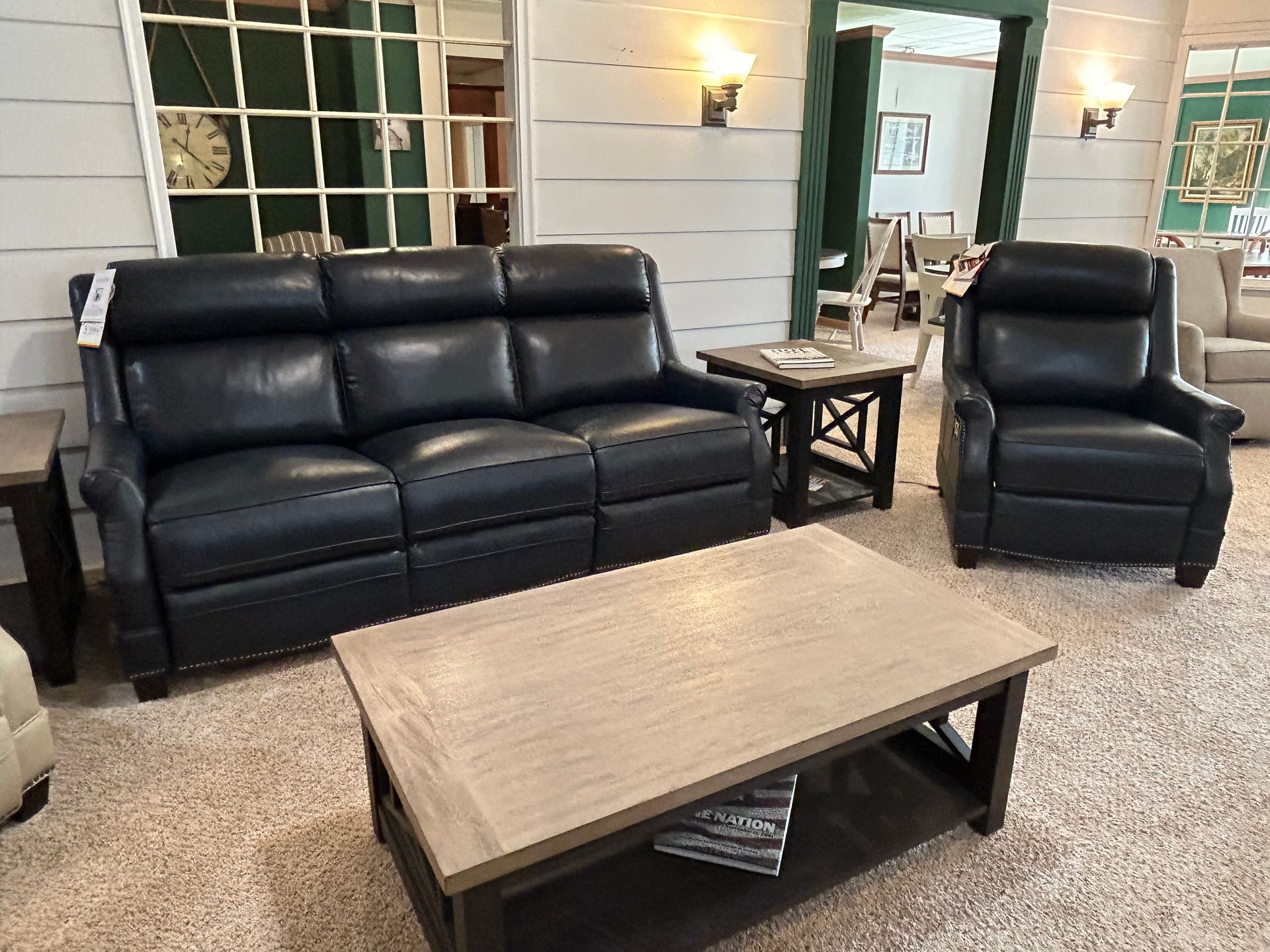 Living room with a black leather couch, recliner, and wooden coffee table.