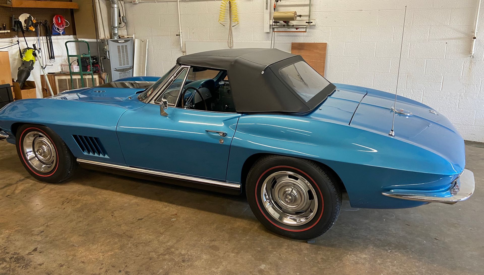 Blue convertible car with black top, parked in a garage.