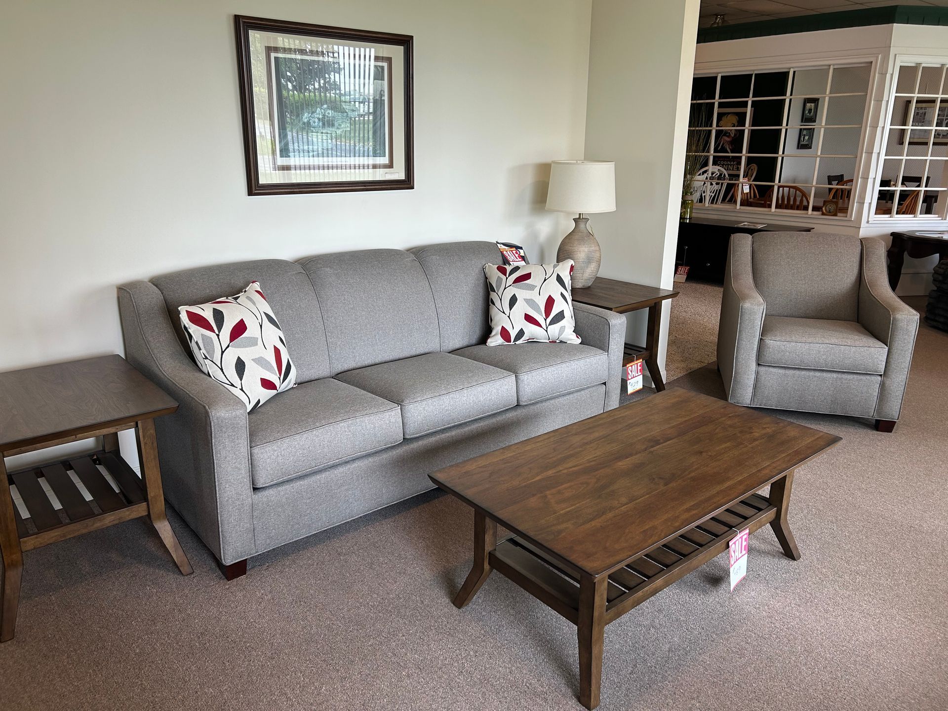 Living room: gray sofa with pillows, armchair, and wooden tables on carpet.