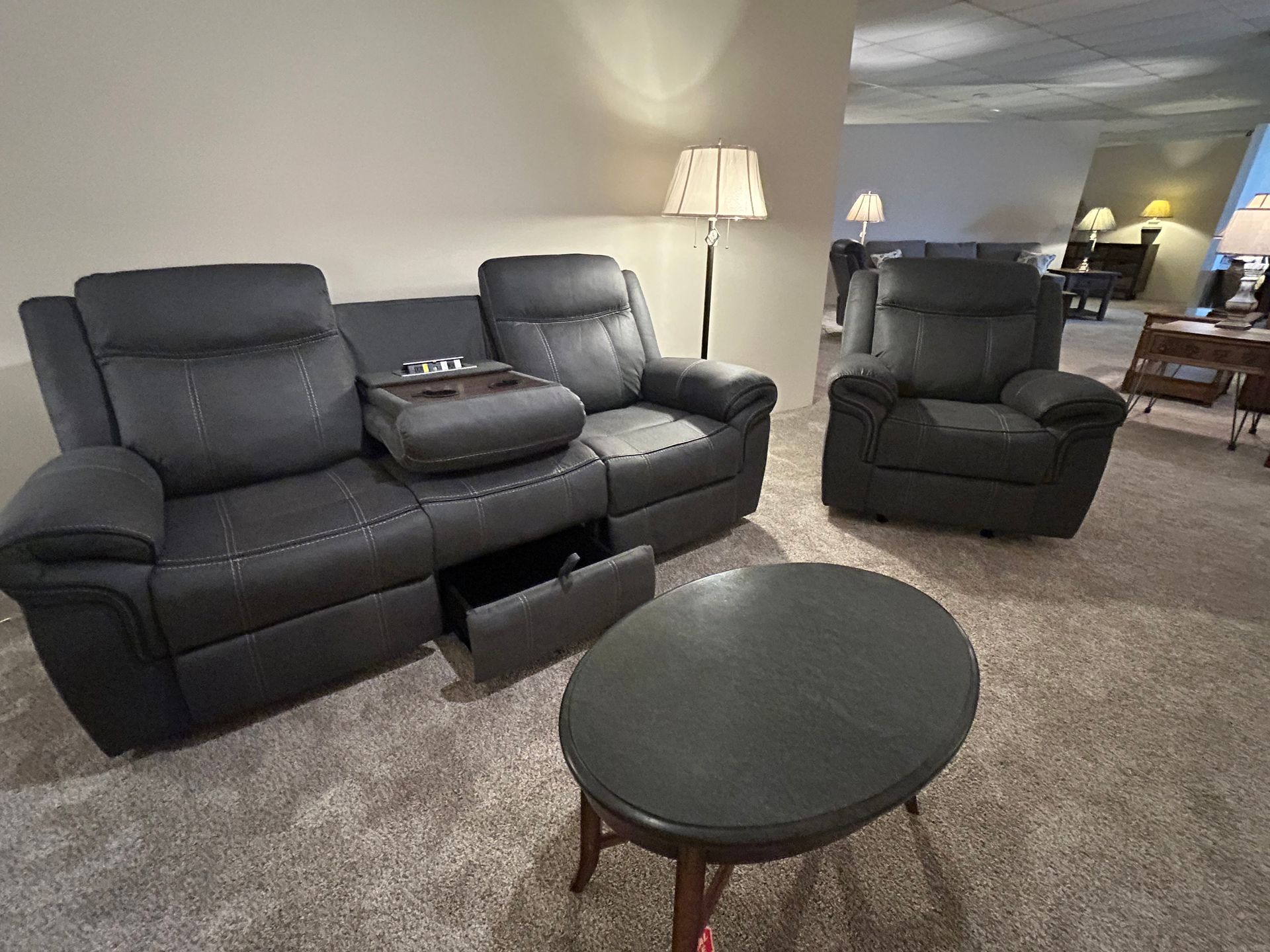 Dark gray recliner sofa and armchair with coffee table in a showroom.