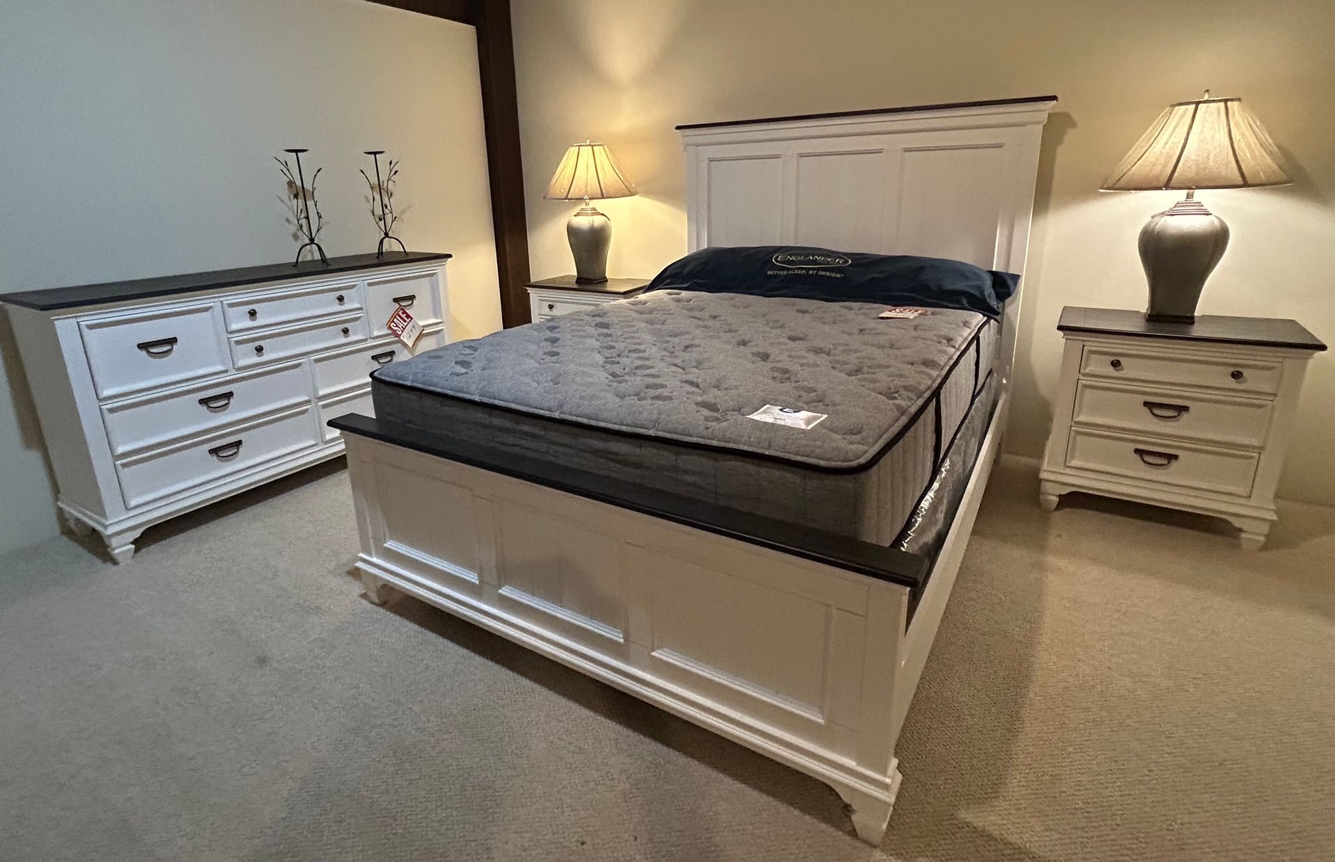 Bedroom set with a white bedframe, dresser, nightstands, lamps, and a mattress.