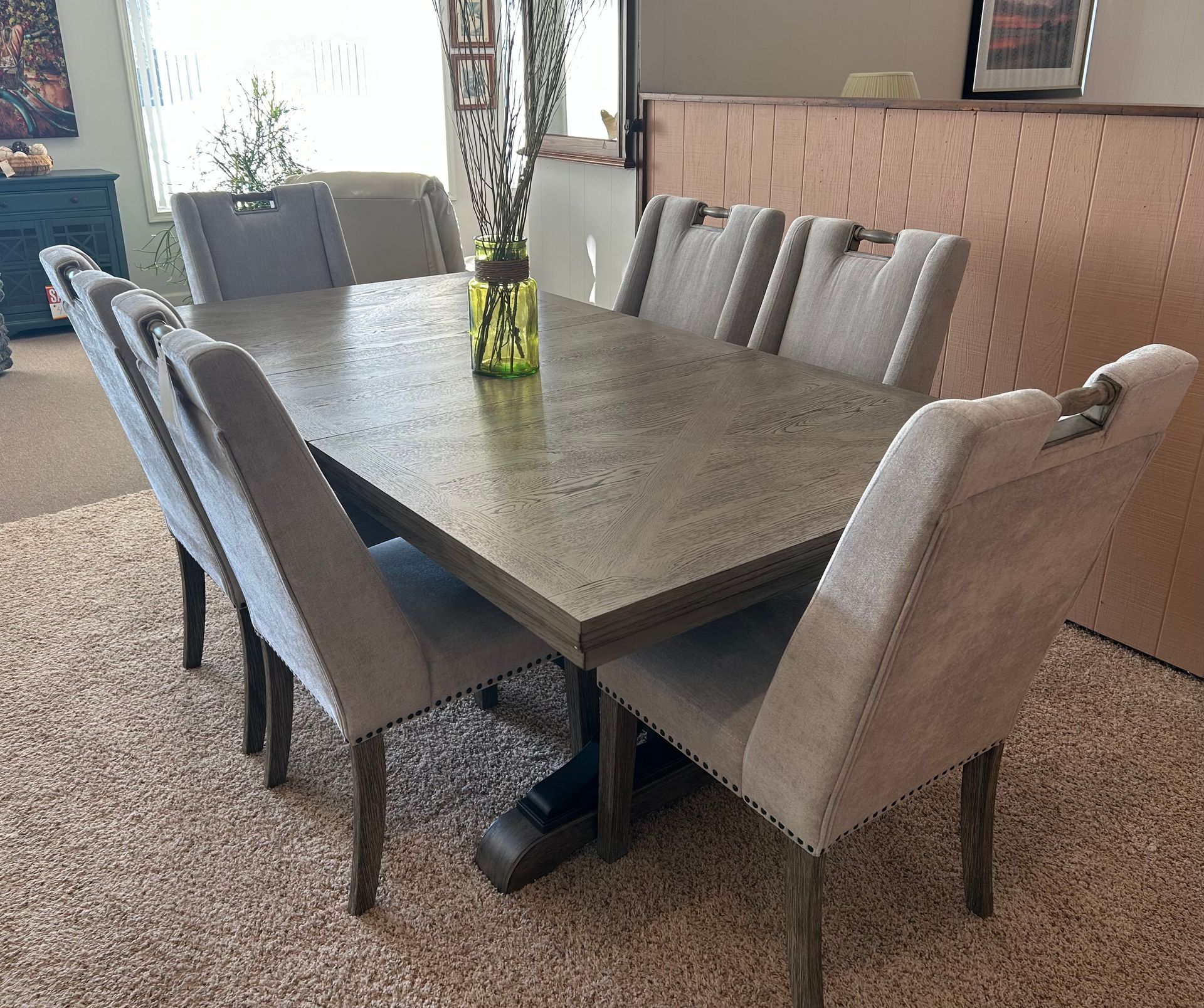 Dining table with eight upholstered chairs; vase of flowers.