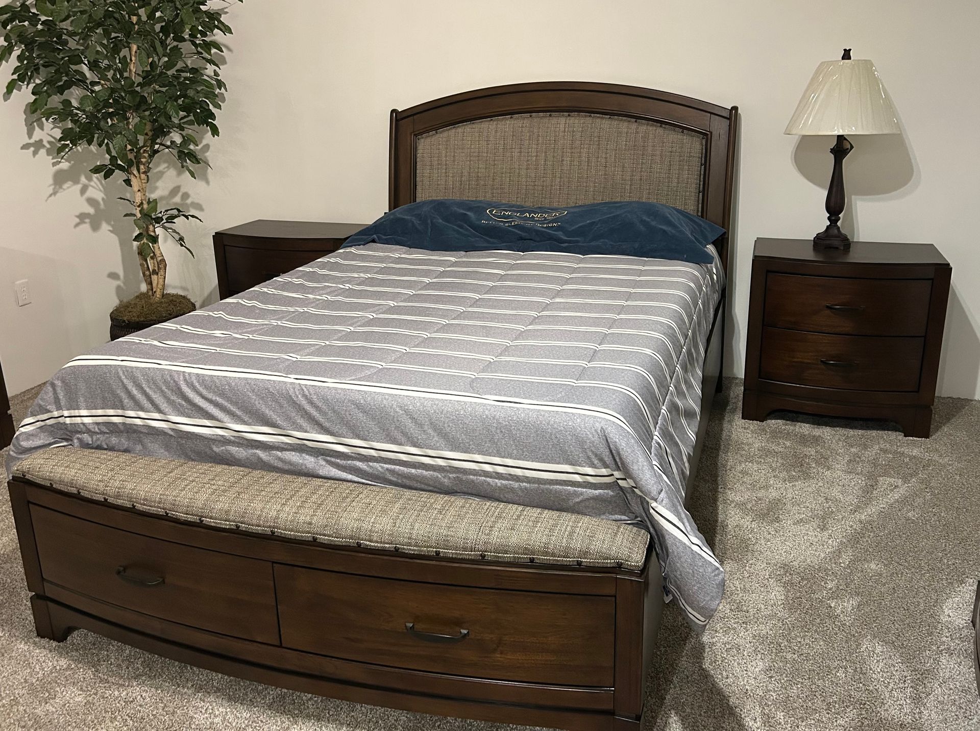 Bedroom with a bed, nightstands, lamp, bench, and an indoor tree.