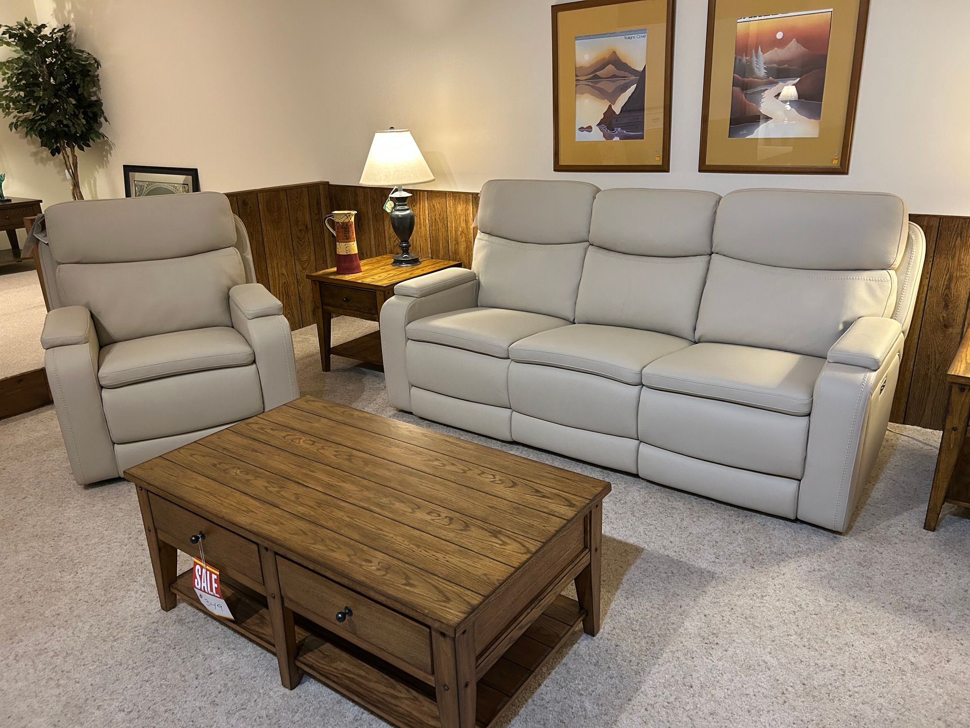 Living room furniture set: light gray sofa and recliner, wood coffee table, lamp, and artwork.