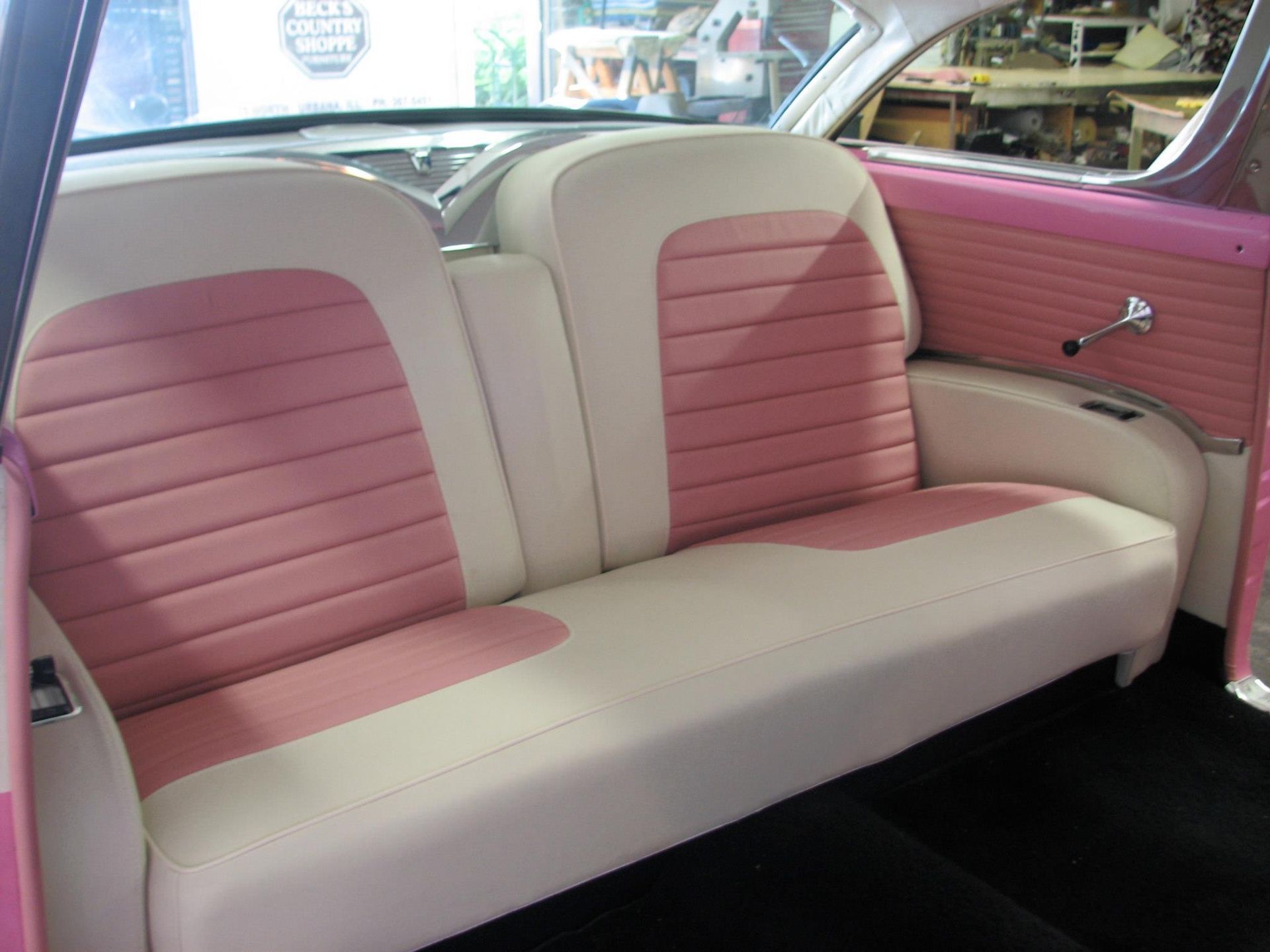 Pink and white vintage car interior with a bench seat.