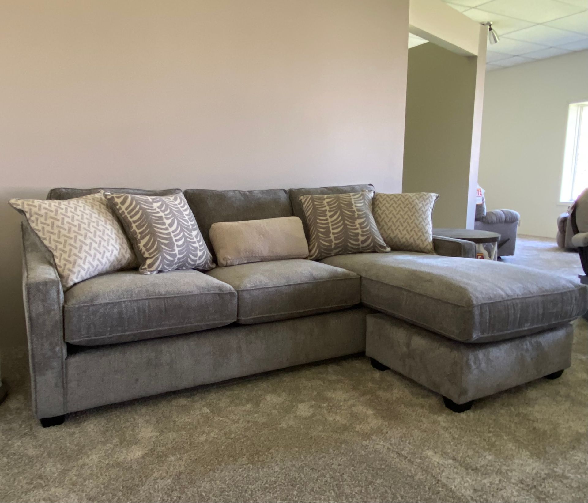 Gray sectional sofa with patterned throw pillows in a neutral-toned room.