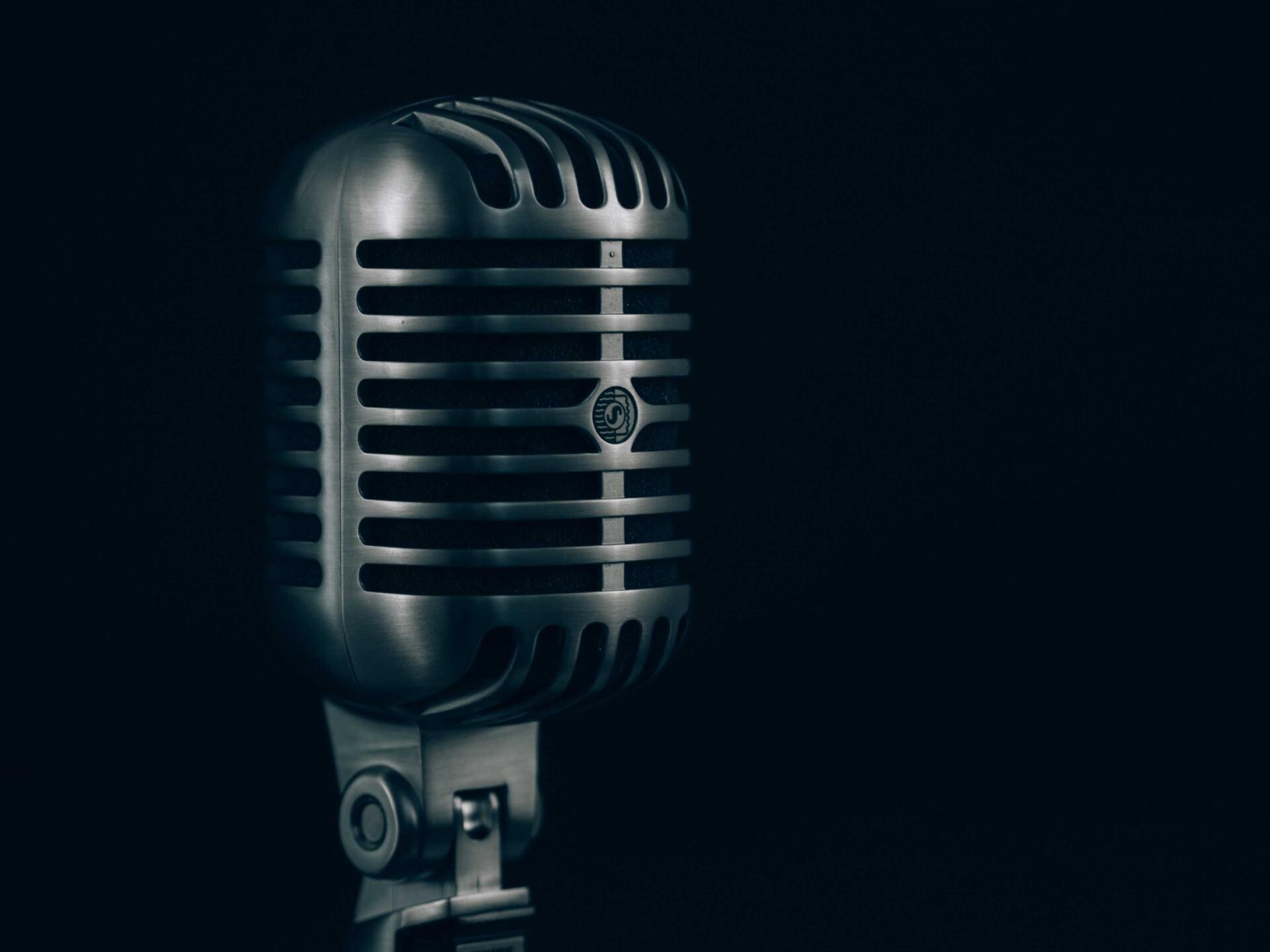 A close up of a microphone on a black background.