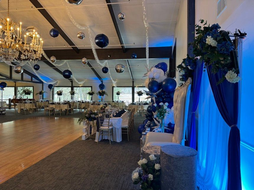 A large room with tables and chairs and balloons hanging from the ceiling.