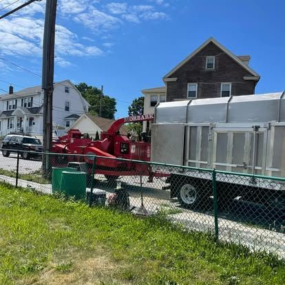 A red wood chipper and truck parked on a street near houses.