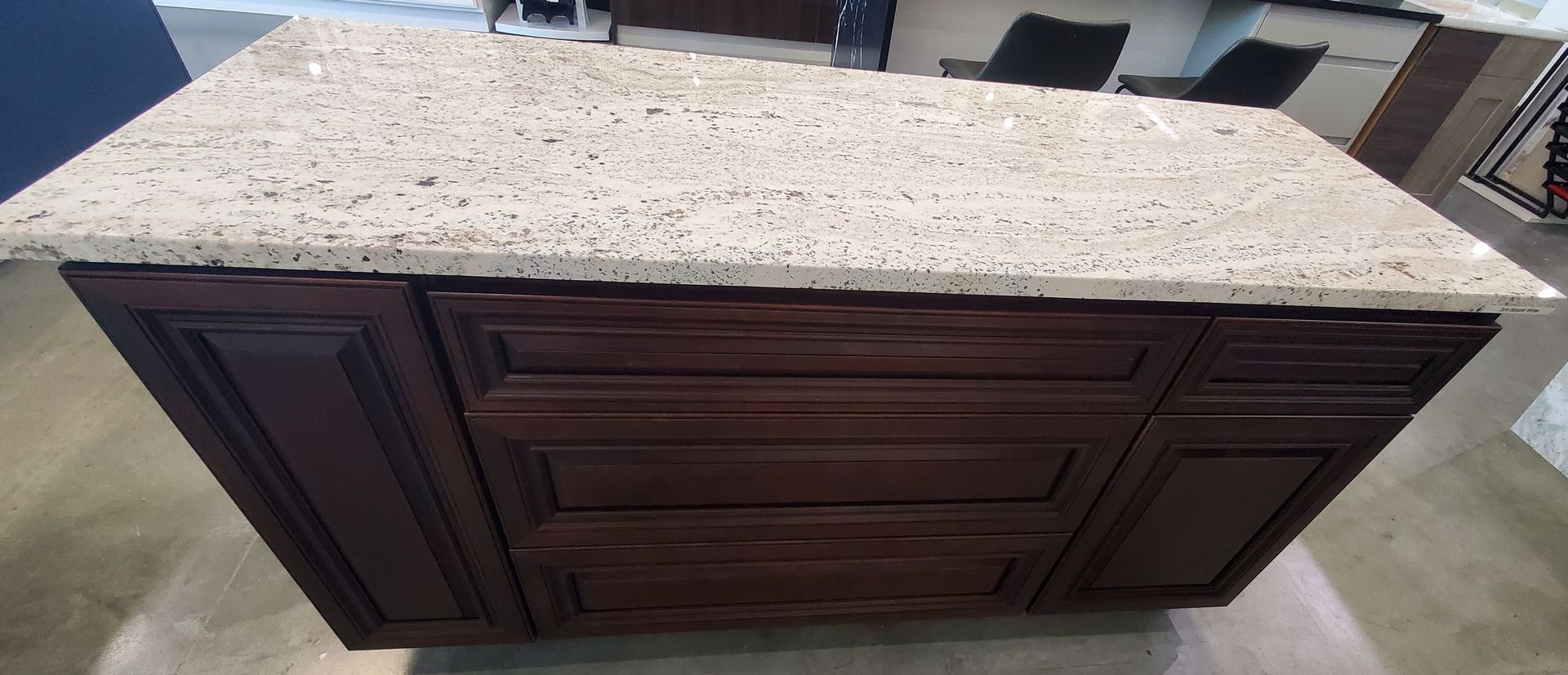 A kitchen island with a granite counter top and brown cabinets.